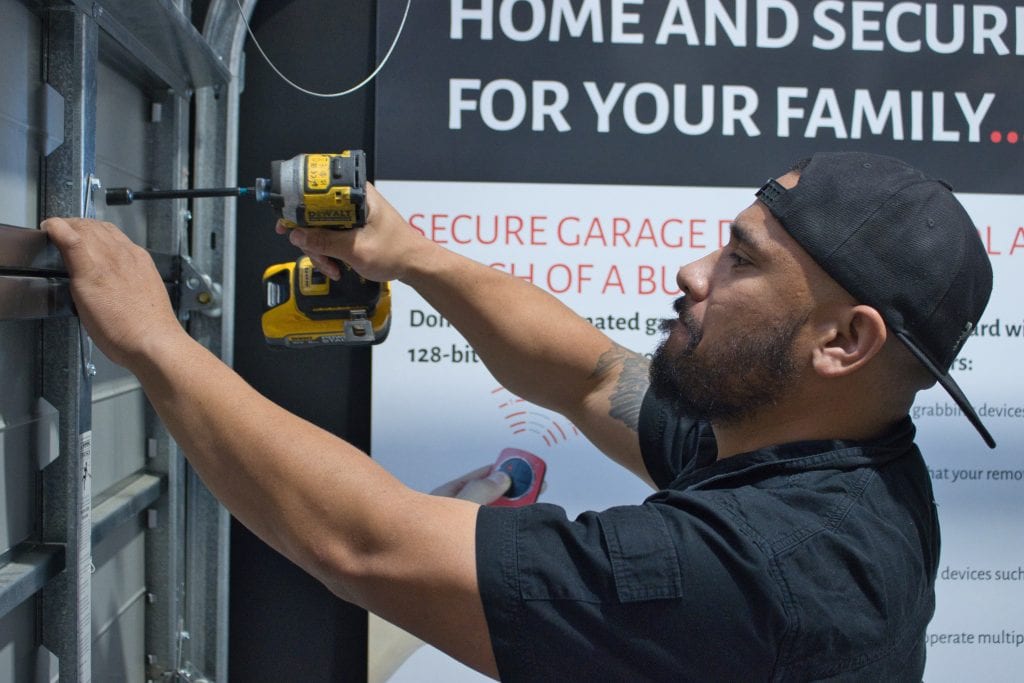 Garage door service visit – Worker drilling a garage rail in place